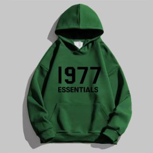 The 1977 Essentials Designer Hoodie in green with a black logo delivers stylish comfort, featuring a soft fleece lining and adjustable hood.