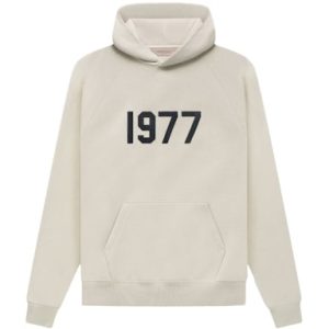 Shop the Fear of God Essentials 1977 Hoodie in Wheat. Cozy knit fabric, adjustable hood, and a perfect blend of style and comfort.