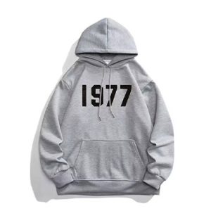 1977 Essentials Grey Hoodie, featuring a timeless design and unmatched comfort. Perfect for everyday wear, this hoodie combines style and functionality.
